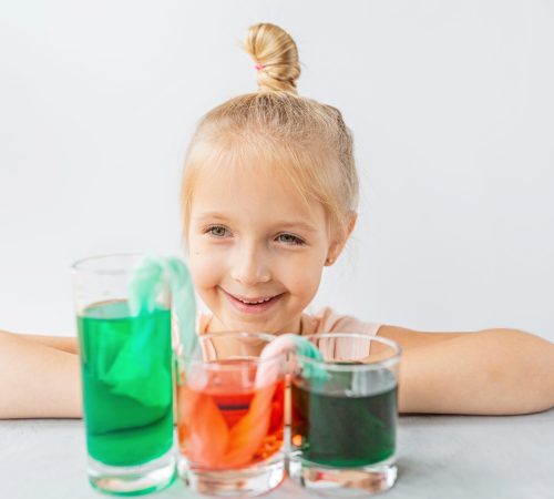 cute little girl six years old doing laboratory experiment with colorful water in classroom. Education science concept. Selective focus. Distance learning during covid-19 coronavirus quarantine. High quality photo